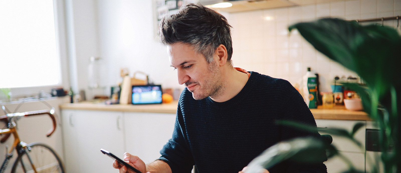 Young man using smartphone in kitchen